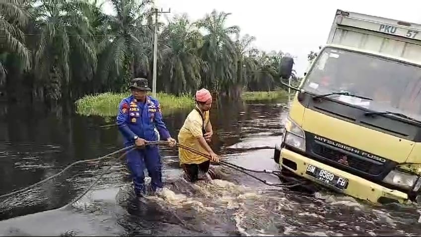 Dua Perwira Bantu Tarik Mobil Box Terperosok di Lokasi Banjir Pelalawan